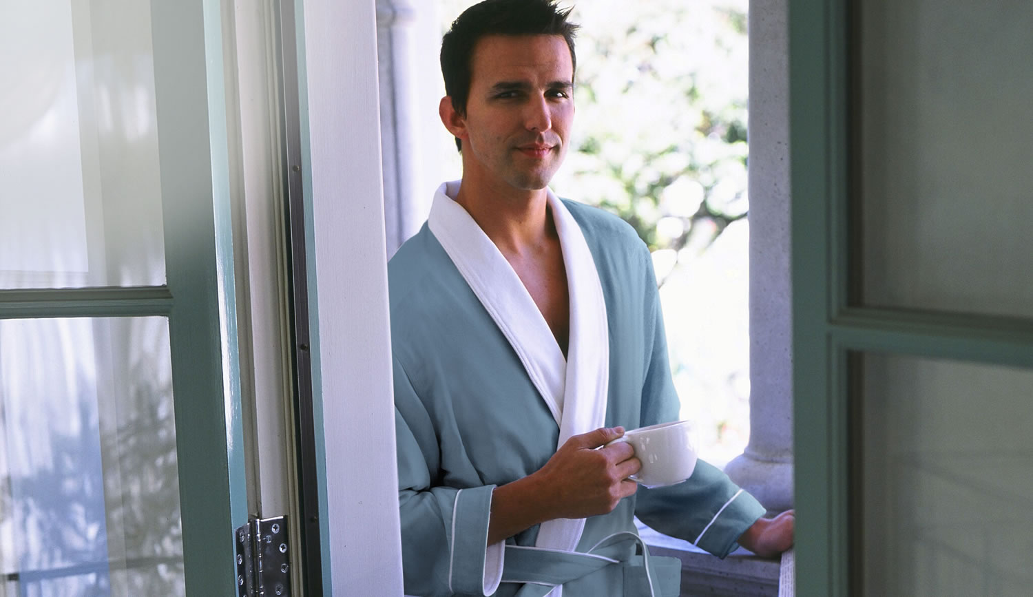 A man relaxing in a white Plush Necessities robe by a window